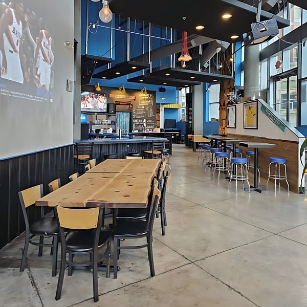 Spacious, modern Korean restaurant interior with long wooden tables, blue accents, and sports screens.