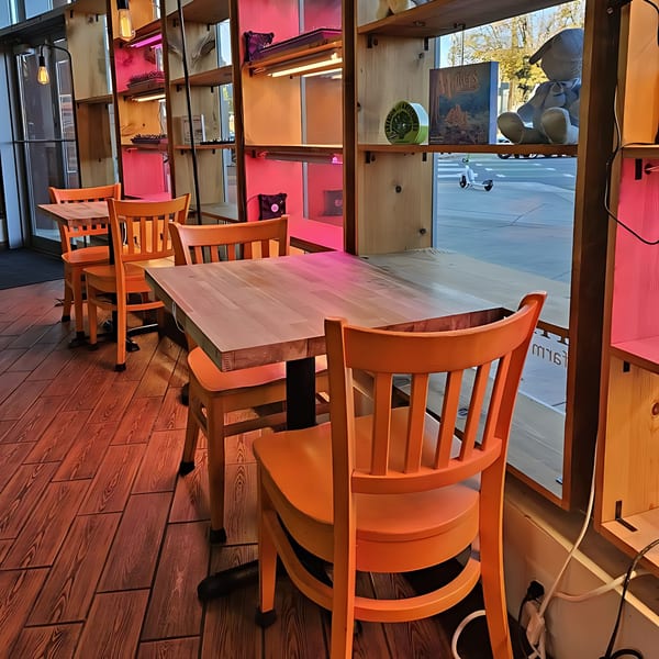 Interior of The Soop, showing orange chairs and wooden tables, with shelves displaying decor and pink lighting.